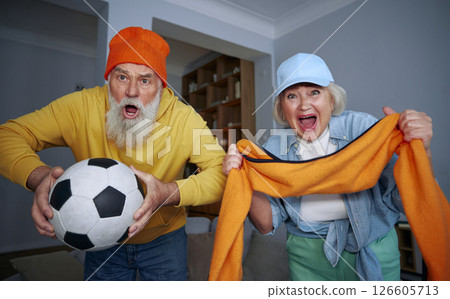 Overjoyed elderly couple watching football match on tv 126605713