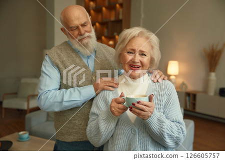Portrait of loving senior couple together over home living room interior Portrait of loving senior couple together over home living room interior 126605757