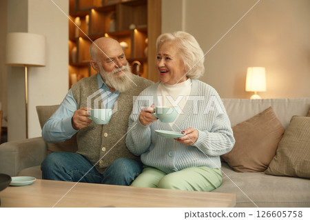 Senior man and woman married couple drinking coffee together in living room Senior man and woman married couple drinking coffee together in living room 126605758