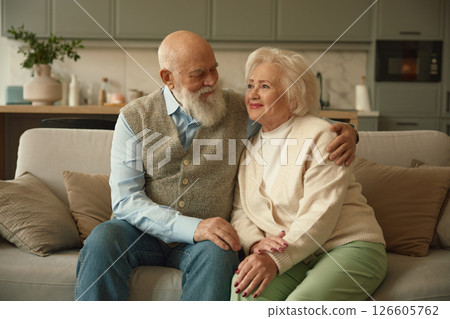 Portrait of happy elderly married couple sitting on sofa in living room 126605762