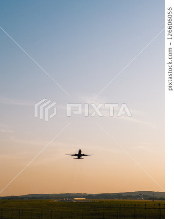Jet plane taking off from airport runway during golden hour, with clear sky and peaceful landscape in background, creating a scenic view of air travel and aviation industry. commercial aviation travel 126606056