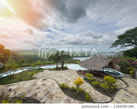 Serene view of infinity pool and lush landscape during sunset in tropical resort 126606196