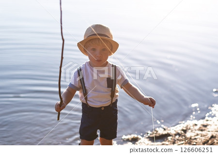 A small toddler boy standing by a lake at sunset. Copy space. 126606251