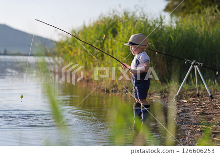 Side view of little boy fishing on lakeshore. 126606253