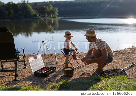 Dad teaching his little boy how to fish by the lake 126606262