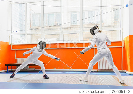 Female fencer making epee hit on opponent sneaker indoors. Female fencer making epee hit on opponent sneaker indoors. 126606360