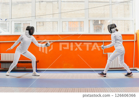 Female fencers preparing to attack in bright fencing hall. 126606366