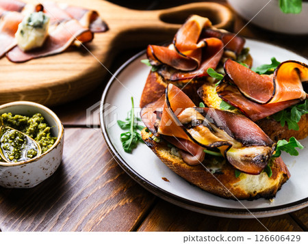 Toasts or bruschettas with bacon, fresh arugula, pesto sauce and blue cheese. Toasts or bruschettas with bacon, fresh arugula, pesto sauce and blue cheese. 126606429