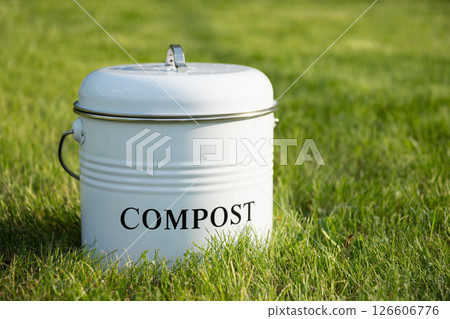 Metal compost bucket with peel vegetables making compost on green lawn. Outdoors. Ecosystem. Sustainable lifestyle 126606776