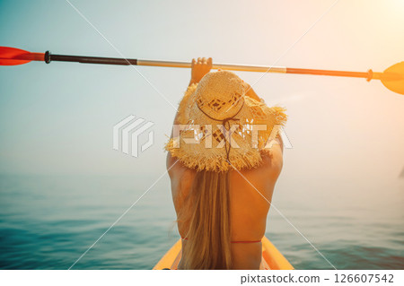 Woman in kayak back view. Happy woman with long hair in a swimsuit and hat floating in kayak on the sea. Summer holiday vacation. Summer holidays vacation at sea. Woman in kayak back view. Happy woman with long hair in a swimsuit and hat floating in kayak on the sea. Summer holiday vacation. Summer holidays vacation at sea. 126607542