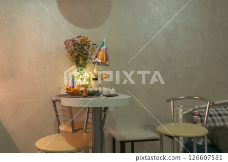 Birthday Cake Table Setting Interior: Romantic indoor birthday celebration; small table with cake, flowers, and drinks; intimate setting. Birthday Cake Table Setting Interior: Romantic indoor birthday celebration; small table with cake, flowers, and drinks; intimate setting. 126607581