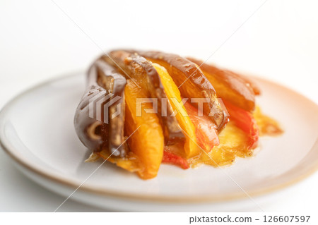 A plate of food with a variety of vegetables, including peppers and eggplant. The dish is served on a white plate and he is a healthy and colorful meal. A plate of food with a variety of vegetables, including peppers and eggplant. The dish is served on a white plate and he is a healthy and colorful meal. 126607597