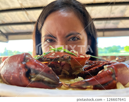 young asian woman showing off crab on plate peeking out from behind crab 126607641