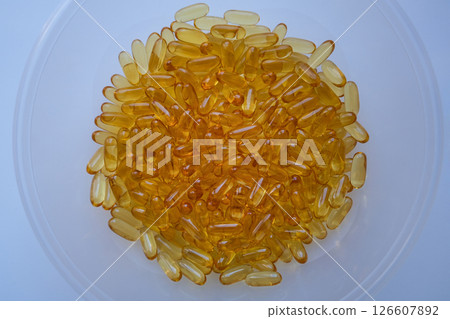 Oil filled capsules (softgel) of food supplements: fish oil, omega 3, omega 6, omega 9. Yellow softgels, top view Oil filled capsules (softgel) of food supplements: fish oil, omega 3, omega 6, omega 9. Yellow softgels, top view 126607892