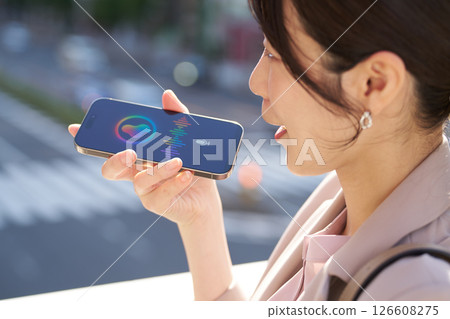A woman talking to a voice assistant outdoors A woman talking to a voice assistant outdoors 126608275