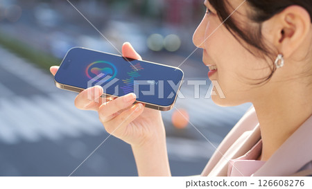 A woman talking to a voice assistant outdoors 126608276