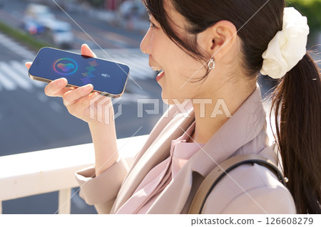 A woman talking to a voice assistant outdoors A woman talking to a voice assistant outdoors 126608279