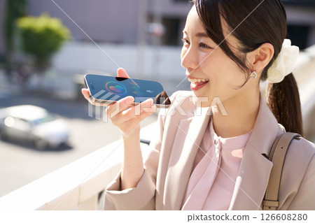 一位面帶微笑的女人與智慧型手機語音助理交談 126608280