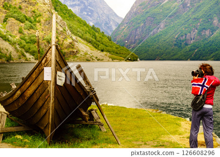 Tourist with camera near old viking boat, Norway 126608296