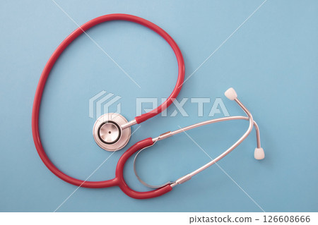 Red stethoscope on blue background. Medical instrument. Health care concept. Red stethoscope on blue background. Medical instrument. Health care concept. 126608666