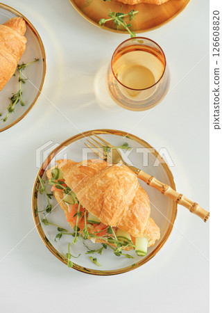 Croissant sandwich with salmon, onions and microgreens on white table. Healthy breakfast. Top view Croissant sandwich with salmon, onions and microgreens on white table. Healthy breakfast. Top view 126608820