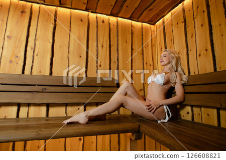 Woman relaxing in sauna enjoying tranquility and self-care session Woman relaxing in sauna enjoying tranquility and self-care session 126608821