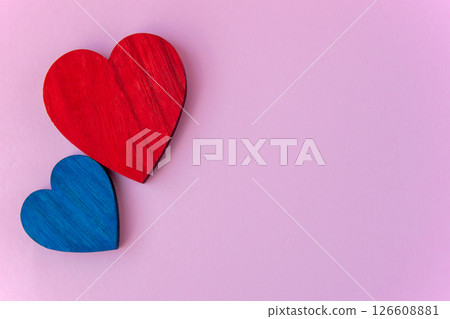 Blue and red wood hearts on the pink background. Space for text. Romantic background for card. Blue and red wood hearts on the pink background. Space for text. Romantic background for card. 126608881