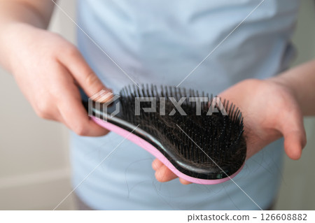 Hands of girl holding black comb with much hairs after hair loss. Problem hair because of stress. Hands of girl holding black comb with much hairs after hair loss. Problem hair because of stress. 126608882