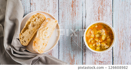 A bowl of soup with chicken broth, vegetables and pasta top view web banner 126608982