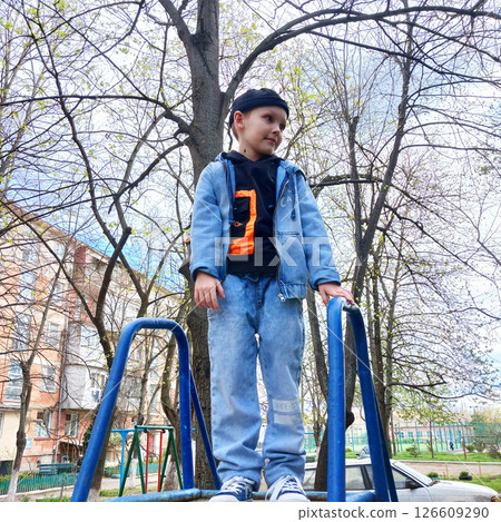 A cheerful boy with a charming smile stands on top of an iron slide 126609290
