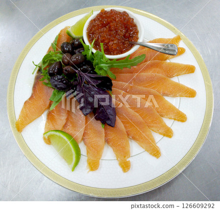 assorted fish: salmon, red caviar, olives and lemon on a large plate 126609292