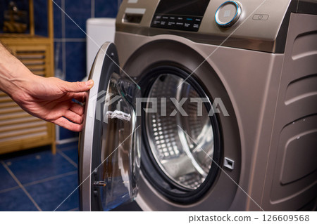 A contemporary modern washing machine with its door open, showcasing laundry inside 126609568