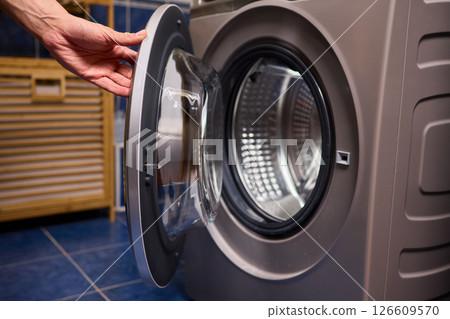 A contemporary modern washing machine with its door open, showcasing laundry inside 126609570