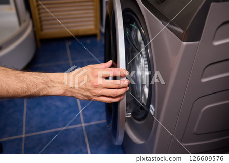 A contemporary modern washing machine with its door open, showcasing laundry inside A contemporary modern washing machine with its door open, showcasing laundry inside 126609576