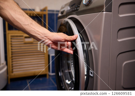 A contemporary modern washing machine with its door open, showcasing laundry inside 126609581
