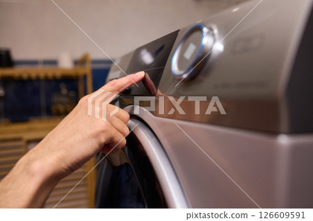 Individual Interacting with a Modern Washing Machines Control Panel for Efficient Laundry Tasks 126609591