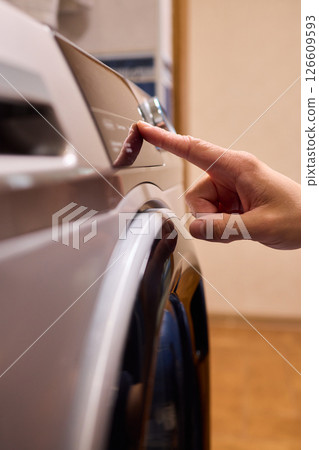 Individual Interacting with a Modern Washing Machines Control Panel for Efficient Laundry Tasks 126609593