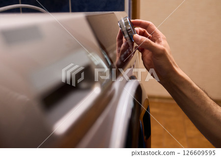 Individual Interacting with a Modern Washing Machines Control Panel for Efficient Laundry Tasks Individual Interacting with a Modern Washing Machines Control Panel for Efficient Laundry Tasks 126609595