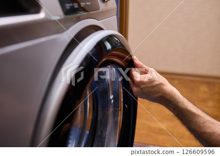 A contemporary modern washing machine with its door open, showcasing laundry inside 126609596