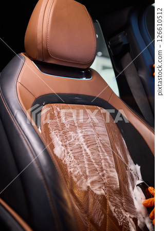 Cleaning a Luxury Car Seat with a Detail Brush and Foam for Maintaining Its Appearance 126610512