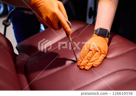 Cleaning a Luxury Car Seat with a Detail Brush and Foam for Maintaining Its Appearance 126610556