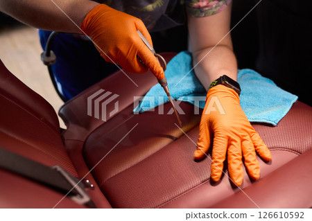Cleaning a Luxury Car Seat with a Detail Brush and Foam for Maintaining Its Appearance 126610592