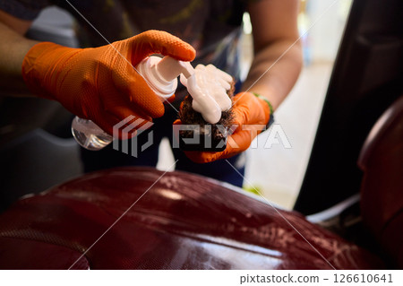 Cleaning a Luxury Car Seat with a Detail Brush and Foam for Maintaining Its Appearance 126610641