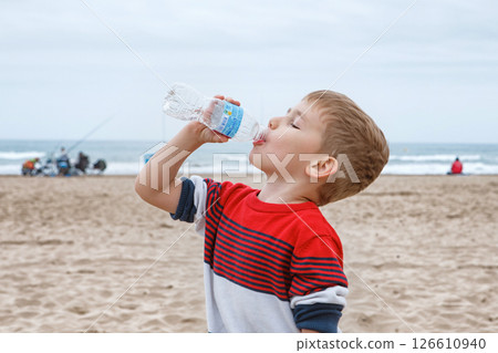Young Child Refreshing Himself by Drinking Water From a Bottle in a Bright Setting 126610940