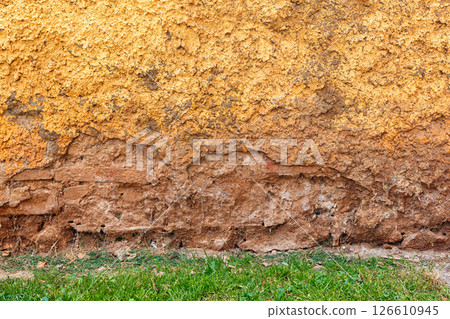 Textured Yellow Wall With Weathered Brick Base and Green Grass at the Bottom, Natural Daylight Textured Yellow Wall With Weathered Brick Base and Green Grass at the Bottom, Natural Daylight 126610945