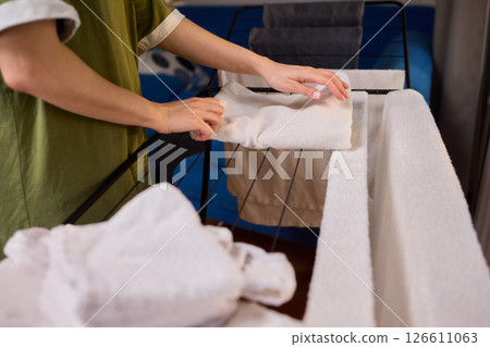 Arranging Freshly Laundered Towels Neatly on a Drying Rack for Optimal Drying and Organization 126611063