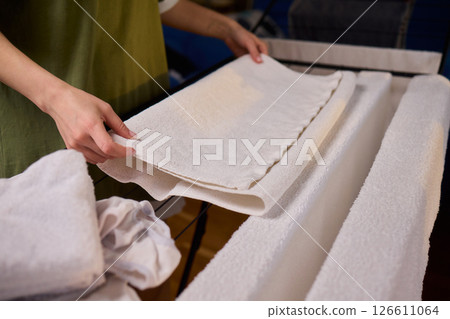 Arranging Freshly Laundered Towels Neatly on a Drying Rack for Optimal Drying and Organization 126611064