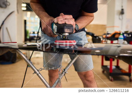 A professional technician expertly polishes glass surfaces in a workshop with precision 126611216