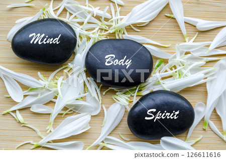 Top view of Mind, Body and Spirit text on zen stones surrounded by flower petals. Meditation ad Inner peace concept Top view of Mind, Body and Spirit text on zen stones surrounded by flower petals. Meditation ad Inner peace concept 126611616