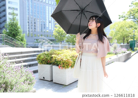 一位女士撐著陽傘沿著長廊散步 一位女士撐著陽傘沿著長廊散步 126611818